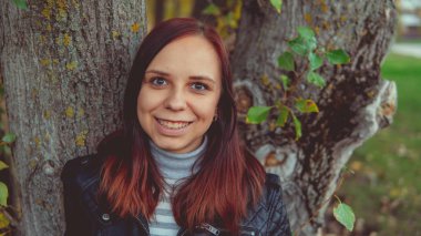 Bir ağacın yanında poz güzel genç kız