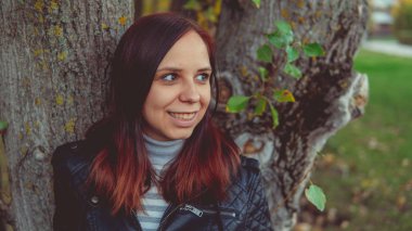 Bir ağacın yanında poz güzel genç kız