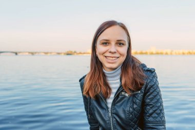 Suya karşı sahildeki poz duygusal kız deri ceketli.