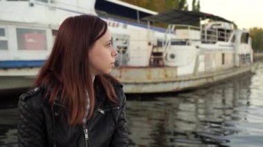 Suya karşı sahildeki poz duygusal kız deri ceketli.