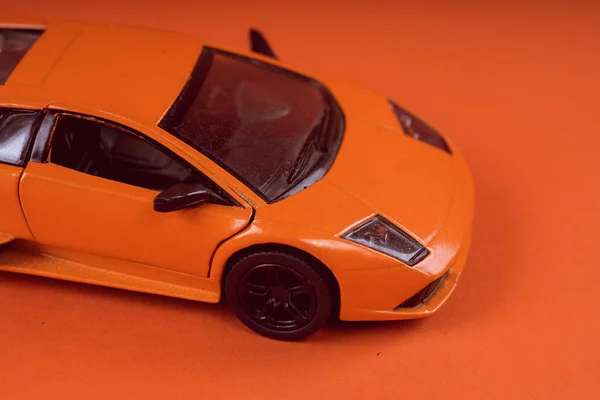 Toy orange car, on orange background. Sports car, close-up shot
