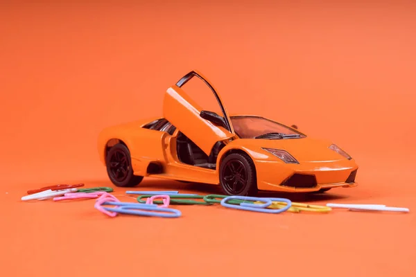 Toy orange car, on orange background. Sports car, close-up shot