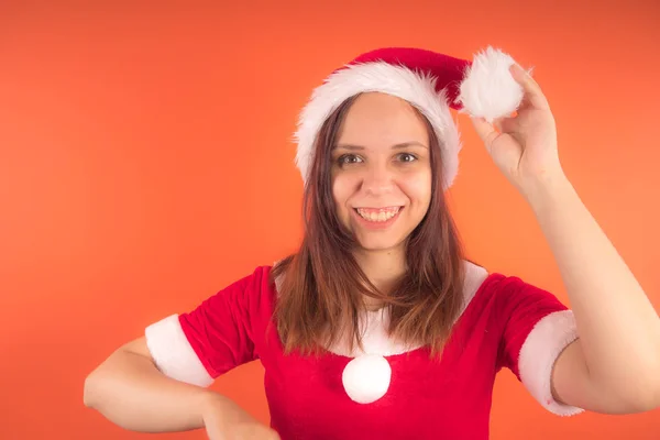 オレンジ色の背景にサンタ クロースとして服を着た若い女の子の肖像画 メリー クリスマスと新年あけましておめでとうございます — ストック写真