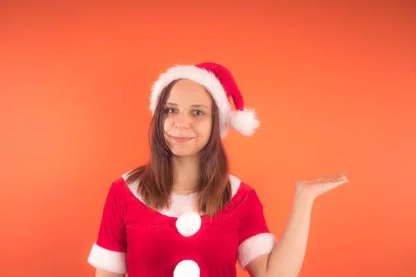 オレンジ色の背景にサンタ クロースとして服を着た若い女の子の肖像画 メリー クリスマスと新年あけましておめでとうございます — ストック写真