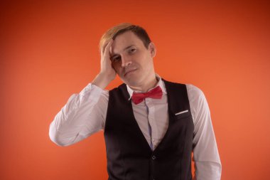 Siyah çelik yelek ve turuncu bir arka plan üzerinde poz kırmızı kelebek ile beyaz bir gömlek yakışıklı bir genç adam