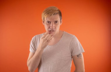 Işık t-shirt turuncu arka plan üzerinde poz içinde güzel genç adam