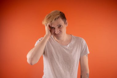 Işık t-shirt turuncu arka plan üzerinde poz içinde güzel genç adam