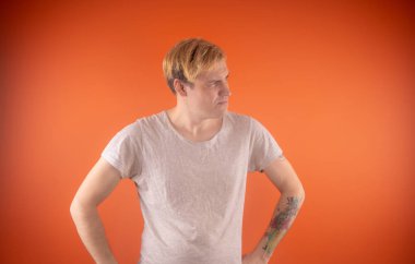 Işık t-shirt turuncu arka plan üzerinde poz içinde güzel genç adam