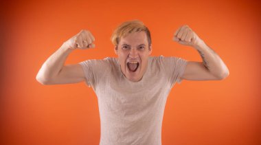 Işık t-shirt turuncu arka plan üzerinde poz içinde güzel genç adam