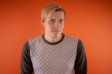 Yakışıklı genç gri süveterli turuncu arka plan üzerinde poz