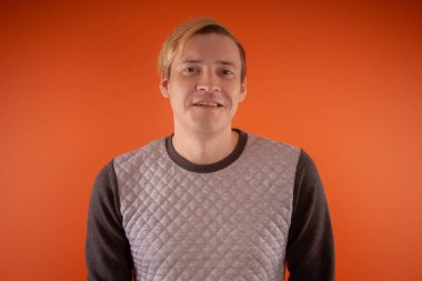 Yakışıklı genç gri süveterli turuncu arka plan üzerinde poz