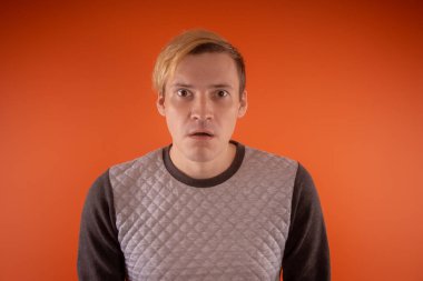 Yakışıklı genç gri süveterli turuncu arka plan üzerinde poz