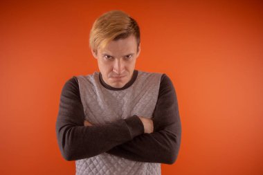 Yakışıklı genç gri süveterli turuncu arka plan üzerinde poz