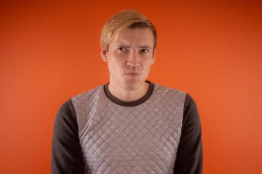 Yakışıklı genç gri süveterli turuncu arka plan üzerinde poz