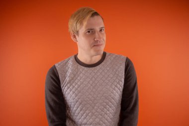 Yakışıklı genç gri süveterli turuncu arka plan üzerinde poz