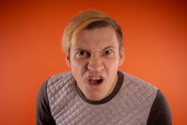 Yakışıklı genç gri süveterli turuncu arka plan üzerinde poz