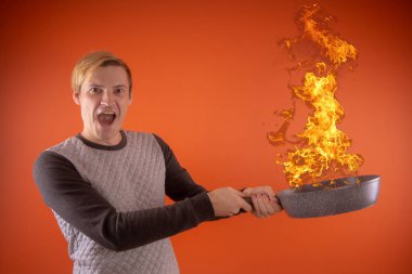 Bir tavada portakal bir arka plan üzerinde onun elinde duygusal adam. Alevler içinde yanan bir kızartma tavası sürer. Kavram, adam özel bir şeyler hazırlar