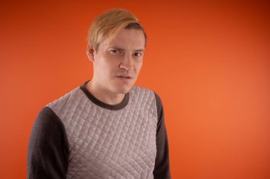 Yakışıklı genç gri süveterli turuncu arka plan üzerinde poz