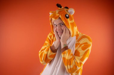 pijama bir zürafa şeklinde. turuncu bir arka plan üzerinde bir adam duygusal portresi. elbiseli çılgın ve komik adam. Çocuk partilerine için animatör