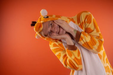 pijama bir zürafa şeklinde. turuncu bir arka plan üzerinde bir adam duygusal portresi. elbiseli çılgın ve komik adam. Çocuk partilerine için animatör