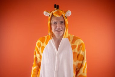 pijama bir zürafa şeklinde. turuncu bir arka plan üzerinde bir adam duygusal portresi. elbiseli çılgın ve komik adam. Çocuk partilerine için animatör