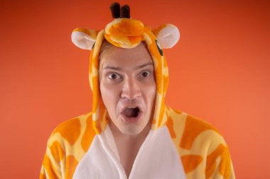 pijama bir zürafa şeklinde. turuncu bir arka plan üzerinde bir adam duygusal portresi. elbiseli çılgın ve komik adam. Çocuk partilerine için animatör