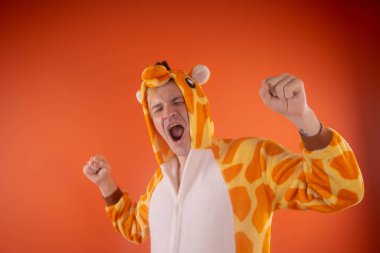 pijama bir zürafa şeklinde. turuncu bir arka plan üzerinde bir adam duygusal portresi. elbiseli çılgın ve komik adam. Çocuk partilerine için animatör