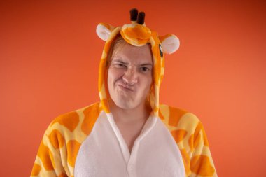 pijama bir zürafa şeklinde. turuncu bir arka plan üzerinde bir adam duygusal portresi. elbiseli çılgın ve komik adam. Çocuk partilerine için animatör