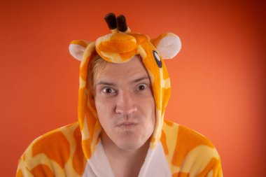 pijama bir zürafa şeklinde. turuncu bir arka plan üzerinde bir adam duygusal portresi. elbiseli çılgın ve komik adam. Çocuk partilerine için animatör
