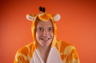 pijama bir zürafa şeklinde. turuncu bir arka plan üzerinde bir adam duygusal portresi. elbiseli çılgın ve komik adam. Çocuk partilerine için animatör