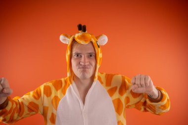 pijama bir zürafa şeklinde. turuncu bir arka plan üzerinde bir adam duygusal portresi. elbiseli çılgın ve komik adam. Çocuk partilerine için animatör