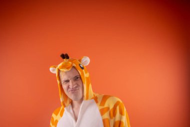 pijama bir zürafa şeklinde. turuncu bir arka plan üzerinde bir adam duygusal portresi. elbiseli çılgın ve komik adam. Çocuk partilerine için animatör