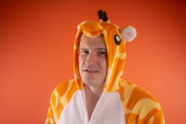 pijama bir zürafa şeklinde. turuncu bir arka plan üzerinde bir adam duygusal portresi. elbiseli çılgın ve komik adam. Çocuk partilerine için animatör