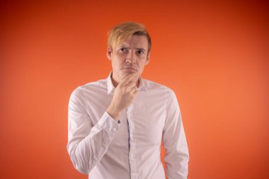 Yakışıklı genç adam düşünceli poz turuncu zemin üzerine beyaz gömlekli