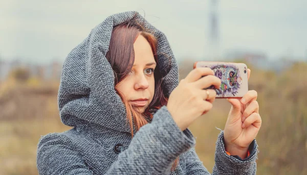 若いスタイルの女の子が公園で携帯電話で Selfie を作るします 秋シーズンの時間 — ストック写真