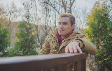 Zemin üzerine sarı ağaçları ile genç beyaz adam. Sonbahar sezonu zamanı. Bir öğrenci parkta yürüyor.