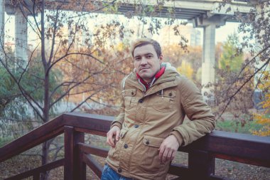 Zemin üzerine sarı ağaçları ile genç beyaz adam. Sonbahar sezonu zamanı. Bir öğrenci parkta yürüyor.