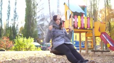 Güzel genç kız salıncakta sallanan bir ceket. kentsel çevre arka plan üzerinde