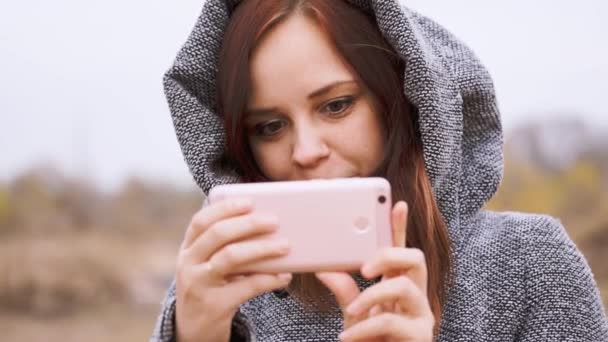 露天的年轻女子在秋天风景的背景下 在智能手机上拍摄风景的照片 — 图库视频影像