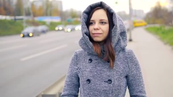 一个穿着灰色外套的年轻女孩走在马路上的栅栏附近 — 图库视频影像