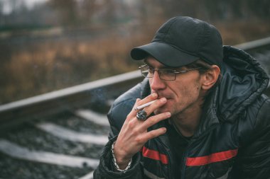 Bir adam sigara içiyor. Gözlüklü adam sigara içiyor. Tütün duman