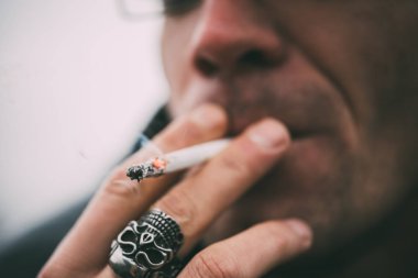 Bir adam sigara içiyor. Gözlüklü adam sigara içiyor. Tütün duman