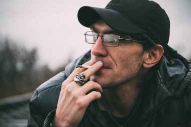 Bir adam sigara içiyor. Gözlüklü adam sigara içiyor. Tütün duman