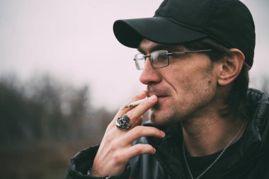 Bir adam sigara içiyor. Gözlüklü adam sigara içiyor. Tütün duman