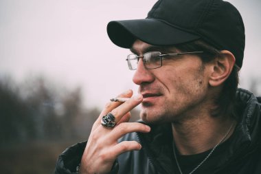 Bir adam sigara içiyor. Gözlüklü adam sigara içiyor. Tütün duman