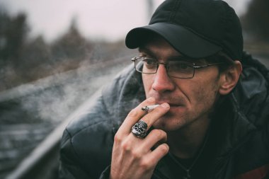 Bir adam sigara içiyor. Gözlüklü adam sigara içiyor. Tütün duman