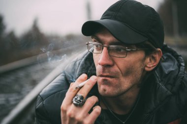 Bir adam sigara içiyor. Gözlüklü adam sigara içiyor. Tütün duman