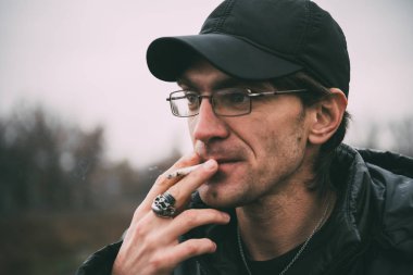 Bir adam sigara içiyor. Gözlüklü adam sigara içiyor. Tütün duman