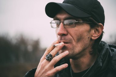 Bir adam sigara içiyor. Gözlüklü adam sigara içiyor. Tütün duman