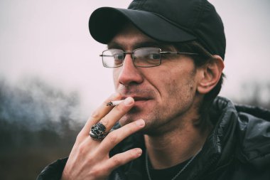 Bir adam sigara içiyor. Gözlüklü adam sigara içiyor. Tütün duman